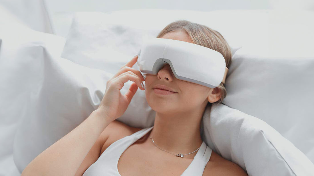 a blond woman using a smart eye massager laying down enjoying her eye massage